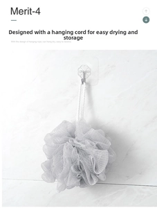 Light gray soft mesh bath sponge with a white rope hanging on a marble bathroom wall