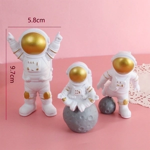 Three gold-masked astronaut cake toppers in resin, including a moon-seated pose, 9.7cm high