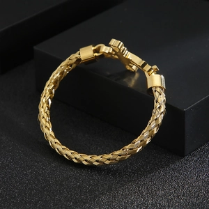 Gold braided stainless steel cable bracelet displayed on a premium black matte stand