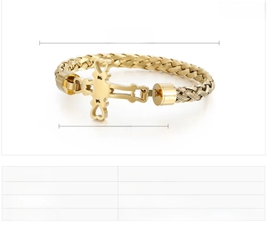 Macro detail of golden stainless steel bracelet featuring woven texture and cross with hearts