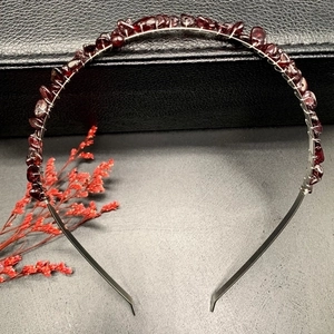 Macro detail of handmade silver headband with dark red crushed crystal stone accents