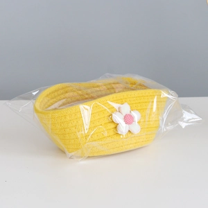 Close-up of yellow woven cotton rope storage basket with decorative pink flower detail