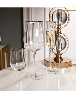 Macro shot of tulip-shaped ribbed glassware set with gold rims on a marble table