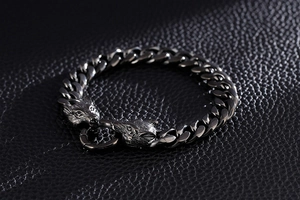 Detail view of punk style stainless steel double wolf head bracelet on black leather background