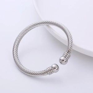 Polished silver wire bracelet with cable texture and round ball terminals on white background