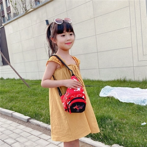 Kids red canvas dinosaur chest bag shown on a young model in an outdoor setting