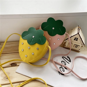 Detail view of strawberry-shaped girl's crossbody bags in pink and yellow with crystals