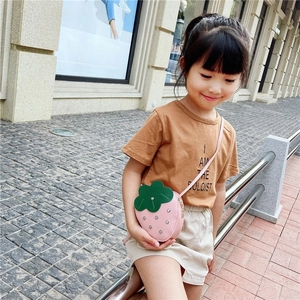 Detail of pink strawberry crossbody bag with rhinestones on a child outdoors