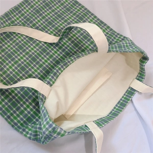 Detailed macro view of the interior lining and internal open pocket of the plaid tote bag