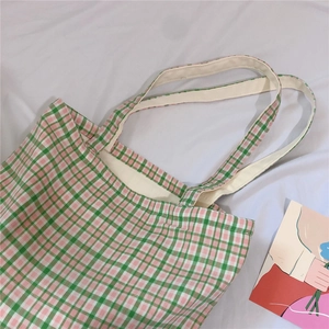 Detail view of pink and green plaid canvas tote bag texture on a white cloth background