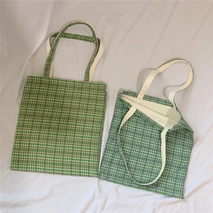 Detailed top view of green and blue checkered canvas tote bags on white fabric