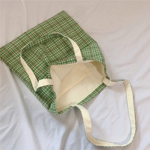 Detail view of the green plaid canvas tote bag with an internal pocket and soft lining
