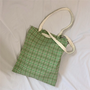 Detail of green and white plaid canvas tote bag with off-white webbing handles
