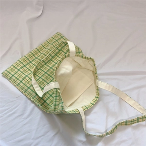 Detail view of green checkered canvas tote bag showing interior pocket and stitching