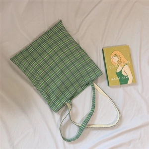 Detail of green and white gingham canvas tote bag laid flat on white fabric background