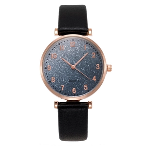Detail of rose gold tonneau watch with blue starry dial and black leather strap