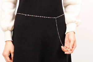 Détail d'une fine chaîne de taille argentée avec des perles rouges et une extension