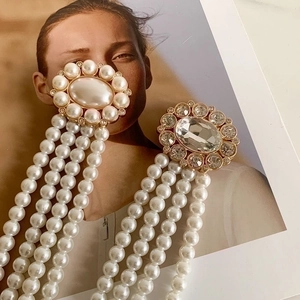 Orecchini pendenti dorati con perle e strass su una rivista di moda elegante