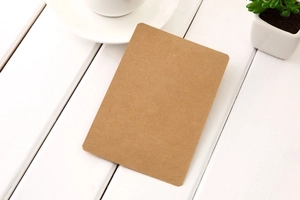 Minimalist rectangular kraft paper card on a white wooden table with a tea cup and plant