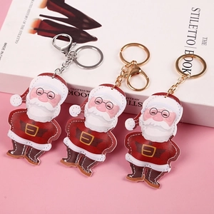 Christmas Santa Claus faux leather keychain with red pom pom and golden clasp on pink background