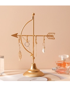 Close-up of golden Cupid's arrow jewelry stand with earrings and rings displayed