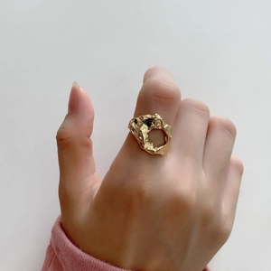 Close-up of gold irregular lava texture open ring worn on finger in minimalist style