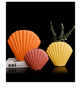 Makroaufnahme von drei muschelförmigen, matten Keramikvasen in Orange, Gelb und Rot