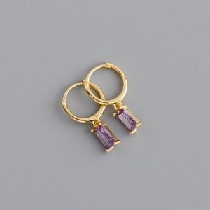 Detailed shot of golden hoop earrings with rectangular purple gemstone pendants