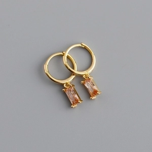 Close-up of golden hoop earrings featuring elegant rectangular champagne crystal pendants