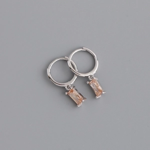 Detail view of silver hinged hoop earrings featuring rectangular champagne gemstones