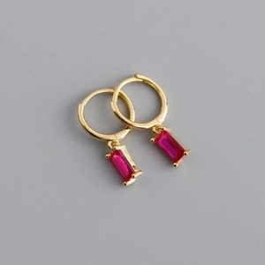 Gold hoop earrings with elegant rectangular ruby red crystal pendants on grey background