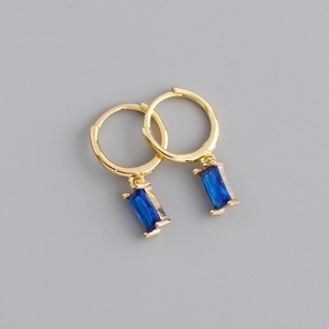 Detail of gold huggie earrings featuring elegant rectangular blue gemstone charms