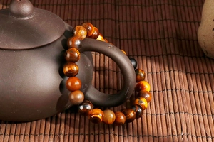 Macro detail of yellow tiger eye bead bracelet with cat-eye effect on a teapot handle