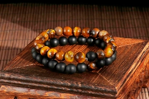 Detail of yellow tiger eye and matte black agate bead bracelets on a wooden base