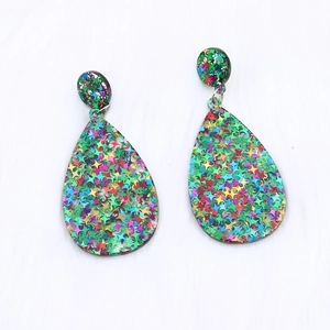 Colorful star sequin teardrop acrylic earrings on soft white faux fur background