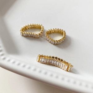 Detail of 925 silver rings with baguette-cut zircon insets on white ceramic plate