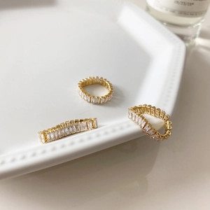 Detailed view of three gold eternity bands with emerald-cut cubic zirconia in a ceramic tray
