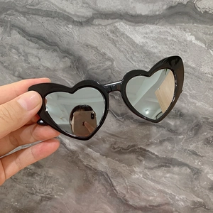 Détail de lunettes de soleil en forme de cœur avec monture noire et verres miroir argent