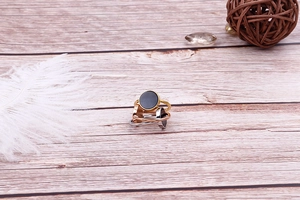 Three-color 18k gold plated stackable rings with black disc charms on wood surface