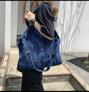 Detail view of large dark blue denim tote bag with functional pockets and wide straps
