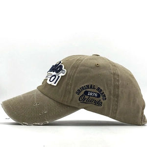 Detail of khaki washed cotton baseball cap with vintage embroidery and worn-out brim effects