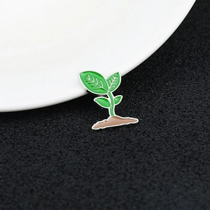 Macro shot of an enamel pin featuring a green plant seedling sprouting from soil