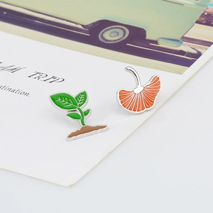 Artistic enamel brooches featuring green sprout and orange ginkgo leaf with silver edges