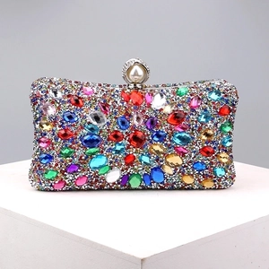 Close-up of vibrant multi-colored rhinestones and pearl clasp on luxury metal evening bag