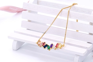 Detail van een gouden verstelbare armband met veelkleurige regenboog zirkoon stenen