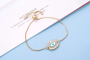 Detail van verstelbare gouden box-kettingarmband met blauw en wit boze oog bedeltje