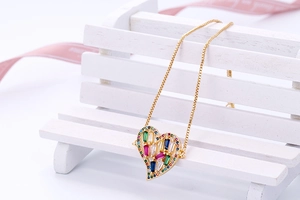 Detail van hartvormige hanger met gekleurde zirkonia op een gouden box-ketting