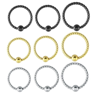 Macro detail of twisted steel piercing rings with ball beads in black, gold, and silver finishes