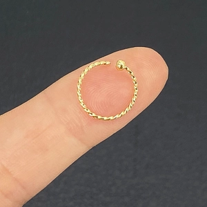 Golden twisted stainless steel nose ring hoop held on finger showing compact size