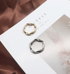 Detail of twisted wave rings in gold and silver finish on silk fabric with card
